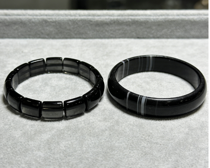 Side-by-side comparison of black obsidian bracelet with glassy luster versus black onyx bracelet with matte banded appearance